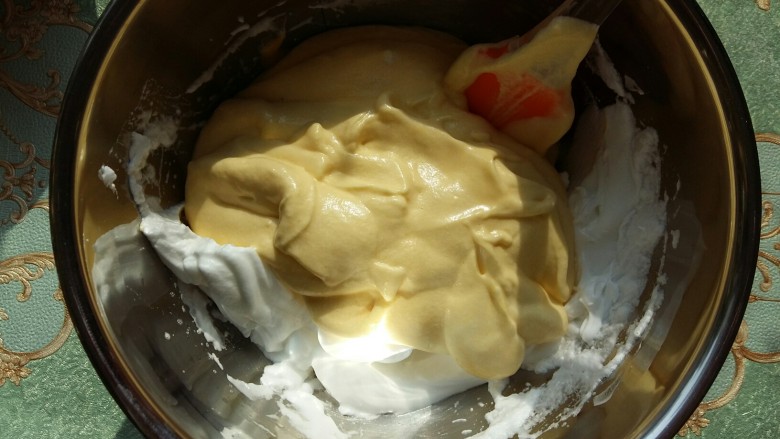 #家有烤箱#南瓜戚风杯子蛋糕,把混合均匀的蛋黄糊倒入剩下的蛋白中。翻拌均匀。
