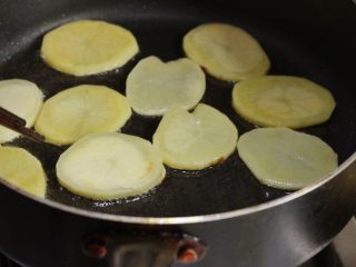香辣干锅土豆片,土豆片一片片均匀放放入锅中煎制，可以分次炸，两面炸至边上略带焦色，捞出控油。