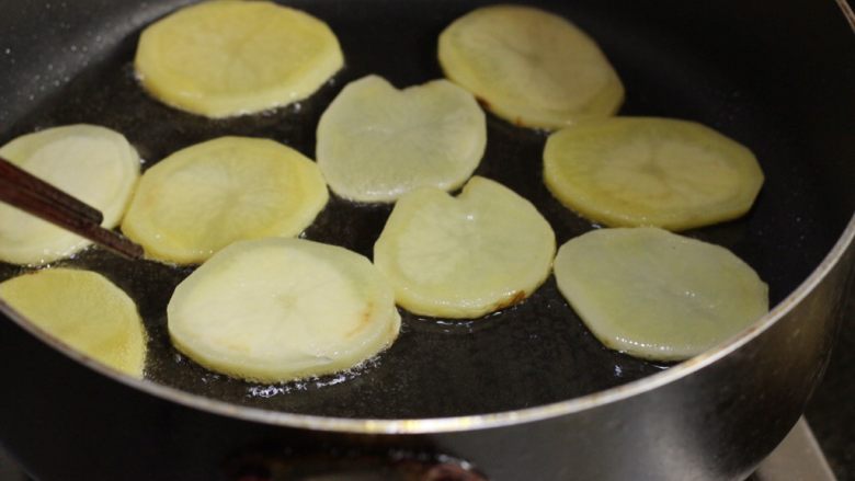 香辣干锅土豆片,土豆片一片片均匀放放入锅中煎制，可以分次炸，两面炸至边上略带焦色，捞出控油。