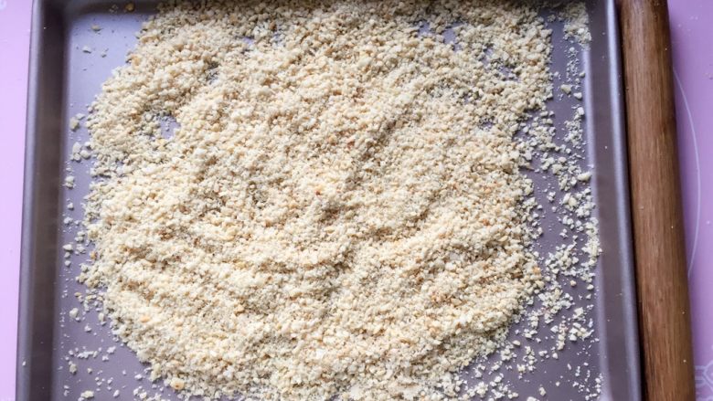 花生酥～#家有烤箱#,将熟花生米放在烤盘中，用擀面杖压碎，不要压成泥，稍微带点颗粒，吃起来口感更好。