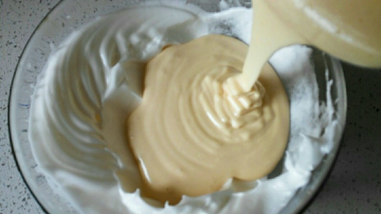 教你做不开裂不回缩的纸杯戚风蛋糕,将搅拌均匀的蛋黄糊倒入剩下的蛋白里。