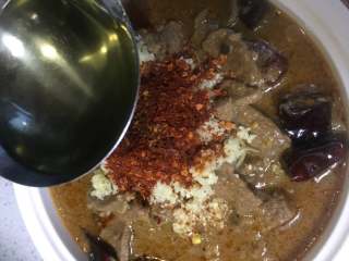 水煮牛肉,锅中烧热 色拉油后，用勺子将油淋在碗中的辣椒粉上。