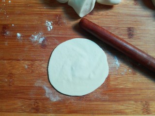 桂香豆沙三角包,撒少许面粉砧板上，取一个面剂子，用手掌心压扁，用擀面杖擀成中间厚，周边薄一点的皮