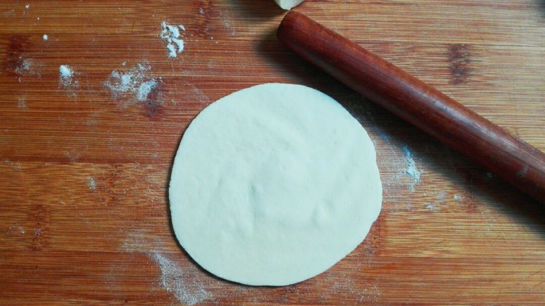 桂香豆沙三角包,撒少许面粉砧板上，取一个面剂子，用手掌心压扁，用擀面杖擀成中间厚，周边薄一点的皮