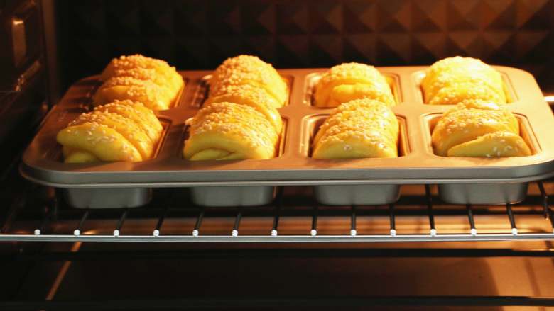 南瓜肉松芝麻包,将模具放入预热好的烤箱中下层，以180度烤20分钟，中途如果上色过快，注意加盖锡纸