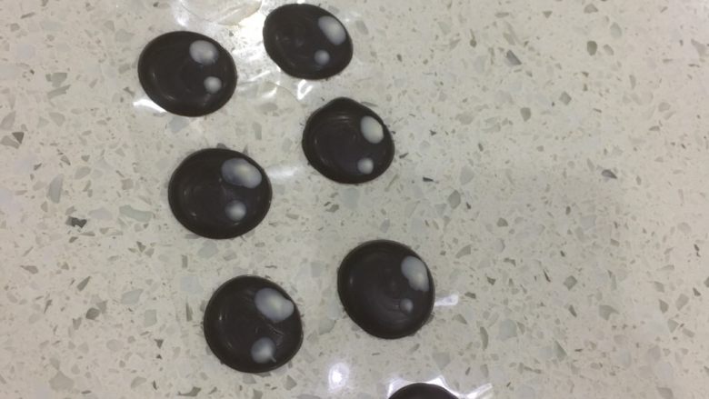 万圣节系列—眼球蛋糕棒,黑巧克力用裱花袋装好，隔水融化，挤成小圆，干透后用牙签粘上白巧克力，在黑巧克的上面画上一大一小的原点。凝固后就可以使用啦。