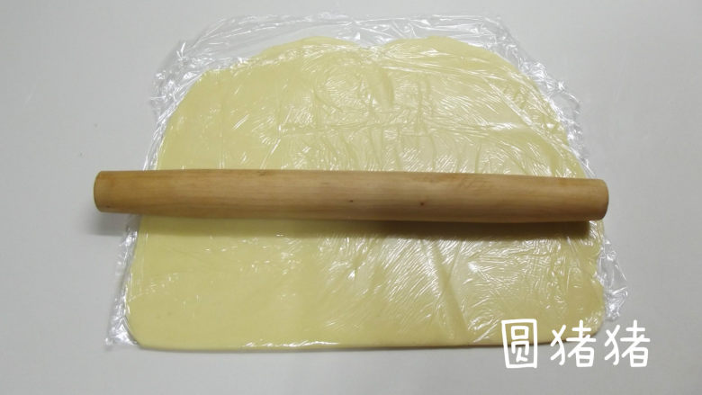 南瓜鬼脸夹心饼干,取一张大的保鲜膜，将面团放入其中，再在表面覆盖一张大的保鲜膜。用擀面棍将面团擀成3mm厚的长方形。 
