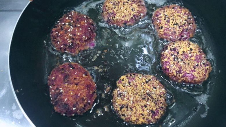 万紫千红香蕉紫薯燕麦饼,把沾满面包糠的小饼放入锅内，小火煎！