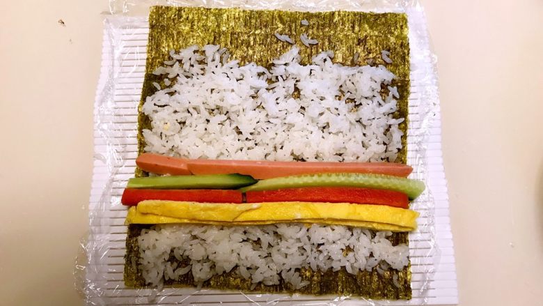 寿司,在米饭上加入蛋皮，胡萝卜条，瓜条，火腿条