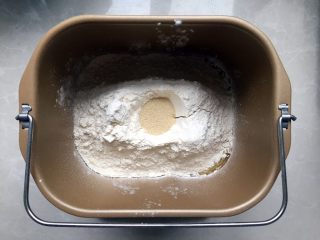 家有烤箱+酸奶椰蓉奶黄面包,将第一部分全部放入面包桶，先放液体再放固体物，最后在面粉表面挖一个小孔放入酵母粉。