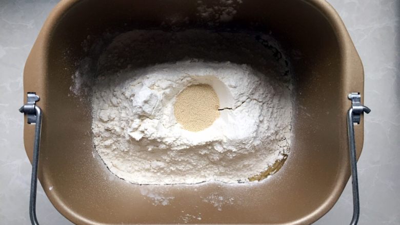 家有烤箱+酸奶椰蓉奶黄面包,将第一部分全部放入面包桶，先放液体再放固体物，最后在面粉表面挖一个小孔放入酵母粉。