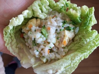 东北菜之儿童饭包,把放放在菜叶子上，用力握一下让饭更紧实，然后裹匀即可。
