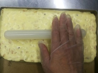 零失败的牛轧糖,放在黄金烤盘中，用擀面杖擀平整。此方的量做出的牛轧糖大约是28*14大小，也就是黄金烤盘的一半量