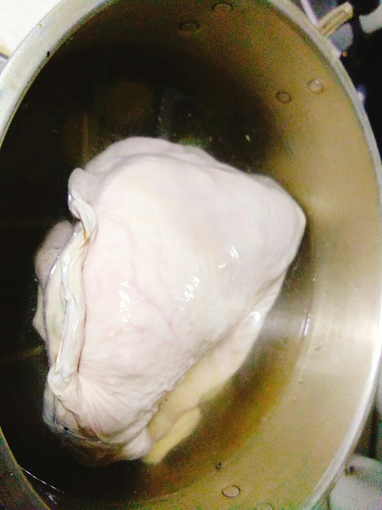 家常养胃荤菜 肚包鸡,锅的底部用筷子架成井字形状，防止粘锅。猪肚包鸡压在上面。加凉水没过猪肚，加入剩余姜片，大火烧开。