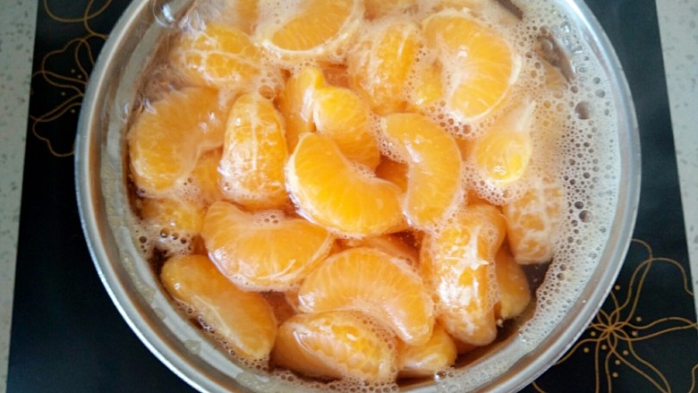 橘子罐头,此时，橘子变得膨胀起来了，再调成小火慢慢的煮，偶尔用勺子搅拌一下，以防粘底。