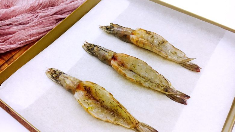 芝士焗大虾,烤盘底下铺上油纸，把腌制好的虾放在烤盘里。