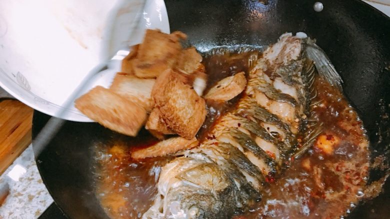 红烧鲤鱼,下豆腐，然后加盖焖煮大概两三分钟，这时一定要开大火，让鱼的汁水渗入豆腐，翻滚的汤汁也使鱼肉更入味