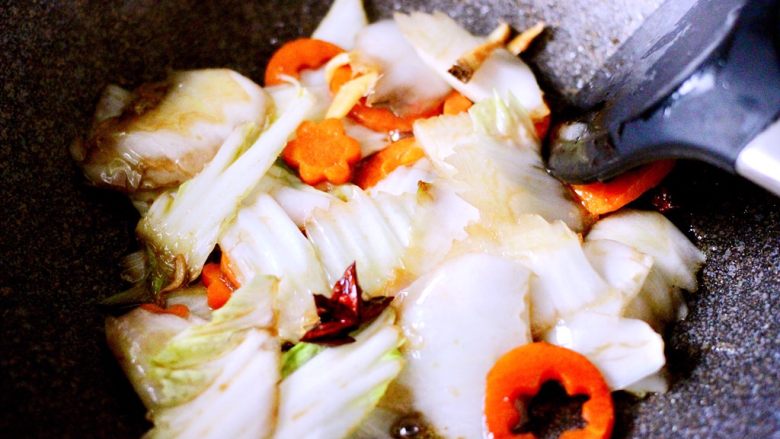 黑酱油+大白菜豆腐丸子炖海鲜,用铲子继续翻炒至白菜帮变软