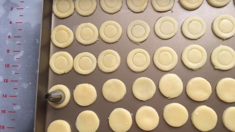 蛋黄纽扣饼干,用小一圈的裱花嘴在圆形的中间按压出一个浅浅的印子