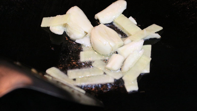 马拉盏面筋焖排骨,猛火热锅，倒入少许生油，锅边起烟后把姜片、蒜头放入锅内爆香
