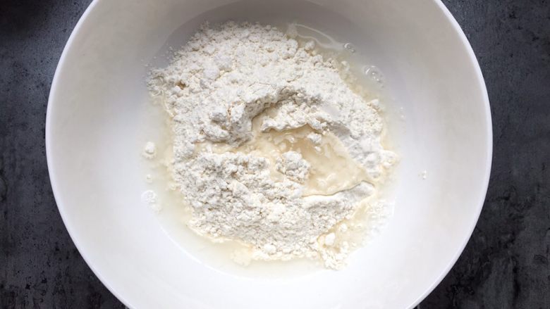 四川乐山名小吃—粉蒸肉卡饼,将面粉加入温水搅匀揉成面团。