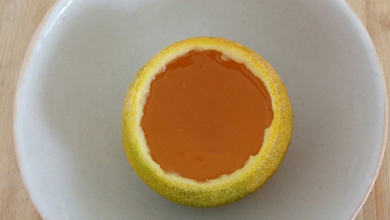 橙子果冻,把冷却的扣扣糖水倒入到橙子碗中，盖上橙皮盖
