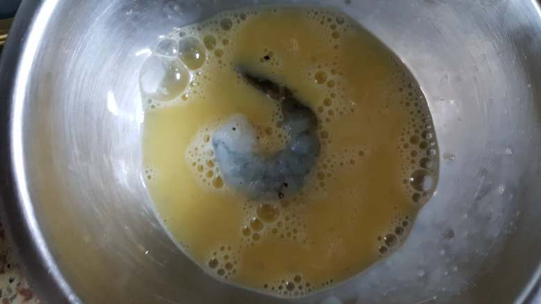 黄金凤尾虾,10.取一个腌制好的虾仁放在鸡蛋液中，使其沾满蛋液。