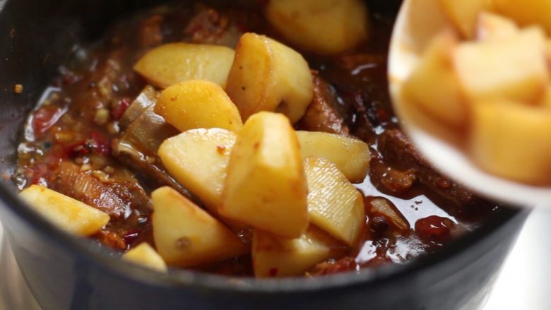 川香土豆炖排骨,加入土豆翻匀，继续炖至汤汁收浓，排骨酥软，土豆粉糯。