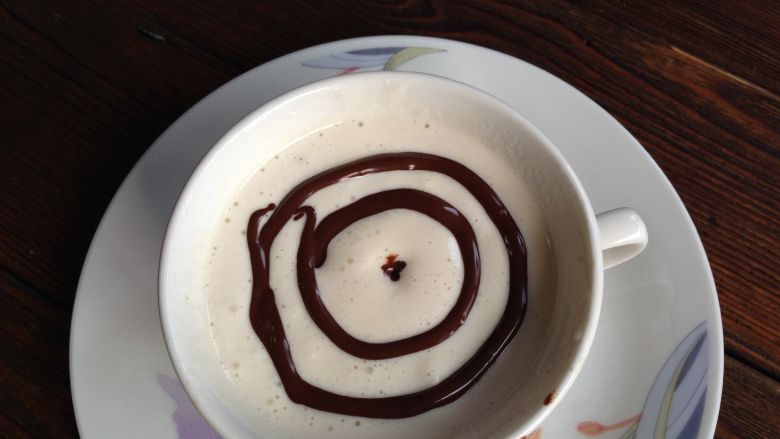 摩卡咖啡,把打好的淡奶油挤入咖啡杯中，奶油表面用<a style='color:red;display:inline-block;' href='/shicai/ 9380'>巧克力酱</a>在咖啡杯中间挤个园点，之后围着圆点画两个同心圆