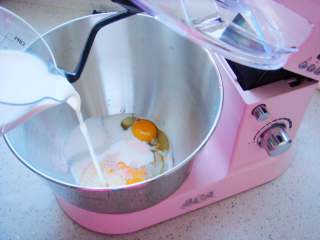 奶香汉堡胚,和面桶里打入两个鸡蛋，倒入盐，白糖，牛奶。