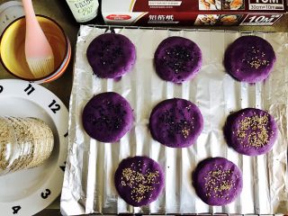 紫薯南瓜饼,准备好一项锡纸，铺入烤盘，刷一层油，把紫薯球按压成紫薯饼，放入烤盘，撒上芝麻