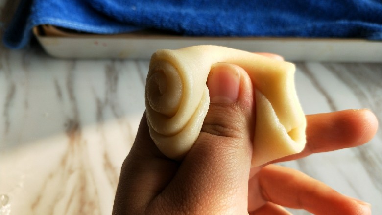 豆沙菊花酥,取一块静置好的面团，大拇指从中间向下压。
