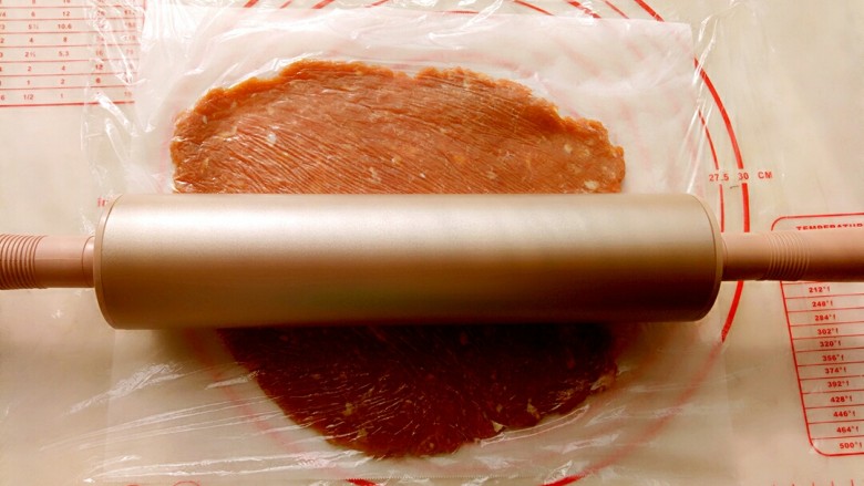 猪肉脯,取三分之一肉馅放到油纸上，上面盖上保鲜膜用阳晨金色擀面杖擀成2毫米左右的薄片。
