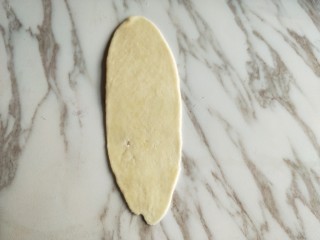 豆沙小酥饼,取一块面团按扁，用擀面杖擀成牛舌状。