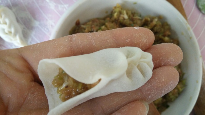 麦穗饺子,从面皮的一头竖着，大拇指和食指分别捏成图中样子