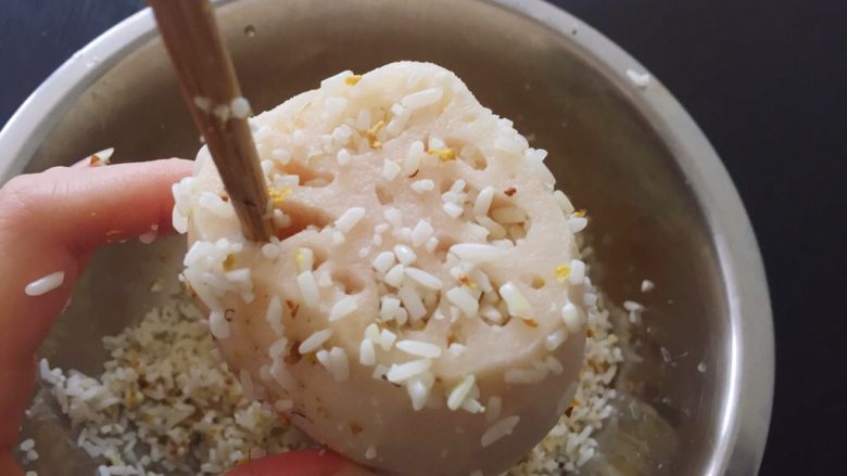 中式甜品—蜜汁莲藕（桂花糖藕）,找一个大盆，底下是糯米，将藕立在盆中填米。先将米抓一小把覆在藕面，再用筷子将米压入孔中。