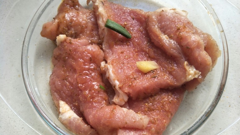 炸猪排,加入葱段和姜片，用手抓匀腌制20分钟左右。
