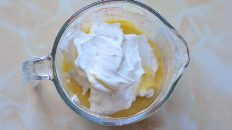 原味纸杯小蛋糕,取1/3蛋白霜放入蛋黄糊中，用刮刀快速翻拌均匀。