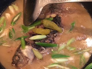鲫鱼炖豆腐,将烧开的水倒入锅中放入小辣椒，小米椒，大蒜苗。开锅后转去砂锅