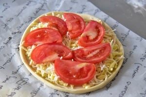 番茄芝士薄底披萨,将少量份量外的橄榄油涂抹在饼底上
铺满芝士，均匀的摆上西红柿片