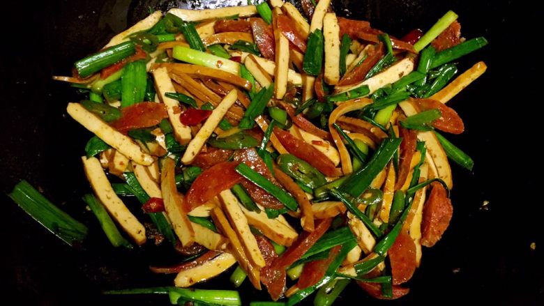 腊肠炒香干,出锅前放入青蒜叶炒至断生即可装盘。