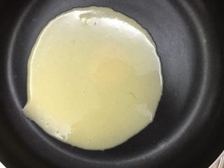 平底锅蛋筒卷,舀一勺面糊到锅里，晃动锅子让面糊均匀摊开，尽量薄一些