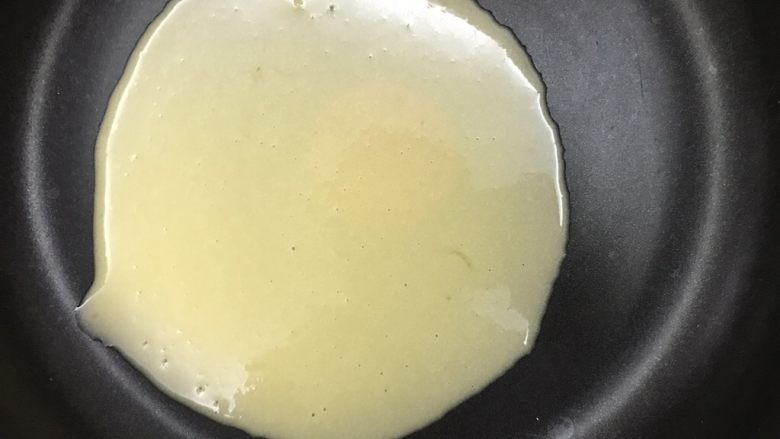 平底锅蛋筒卷,舀一勺面糊到锅里，晃动锅子让面糊均匀摊开，尽量薄一些