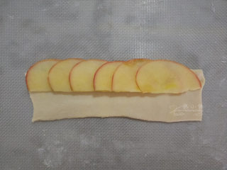 吃掉一朵花——玫瑰苹果挞,根据自己模具尺寸来决定千层酥皮的长度。
我用的是大号的蛋糕连模，酥皮擀成4cm*13cm的条。
在面片上放摆放苹果片，不要摆的太多。