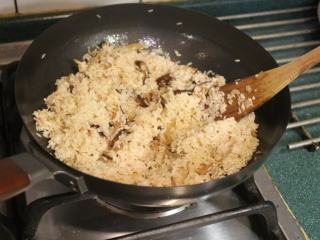 酒香麻油鸡油饭,放入滤干后的米翻炒均匀至半熟。若米已经炒干，可先加约50cc的水，继续拌炒。
