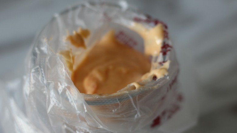 网红胡萝卜奶香网格蛋饼,将裱花袋套在玻璃杯上，把面糊倒入裱花袋中。