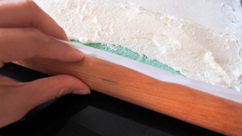 ⭐蓝天白云咸奶油蛋糕卷⭐,然后用擀面杖做辅助垫在油纸下面，进一只手帮忙提起来。