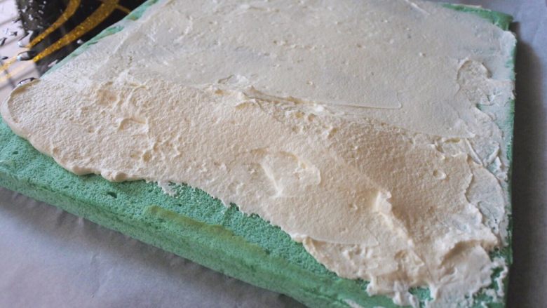 ⭐蓝天白云咸奶油蛋糕卷⭐,将奶油抹在蛋糕面上，靠近自己的那一边抹成小山丘的形状，如图。