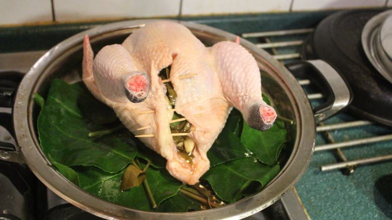 茄苳蒜头鸡,将麻油炒过的蒜头和茄苳叶塞入鸡肚内。也将鸡心、鸡肝也一起塞到鸡肚里。用牙签将鸡肚封起。把鸡放入锅内。