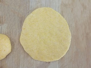 橙汁玉米面饼,用手压成光滑的薄薄的面饼